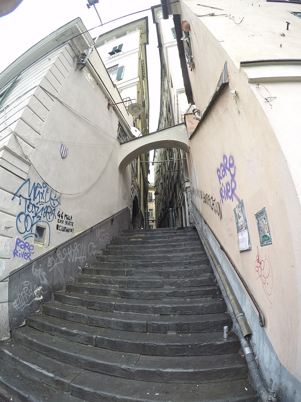 A stepped lane in the old town, climbing between graffitied walls