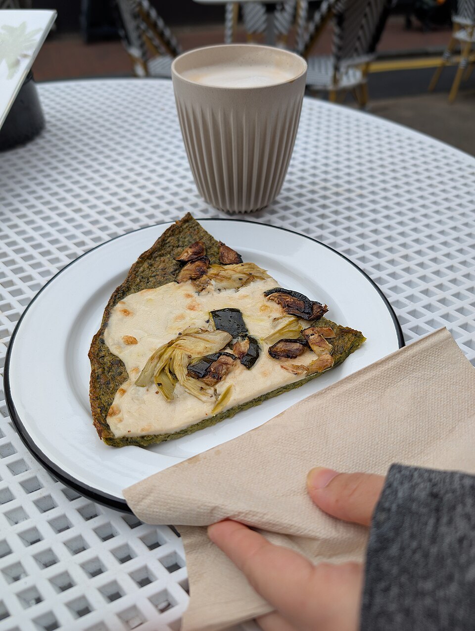 A slice of farinata on paper, taken away with a coffee