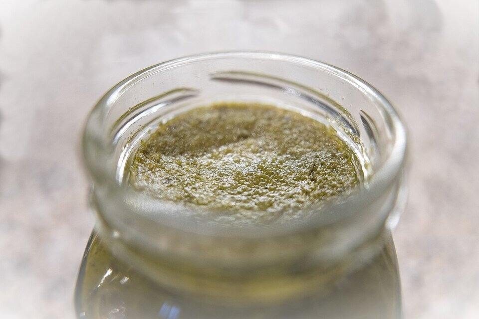 A jar of freshly made pesto, the oil still sitting on top