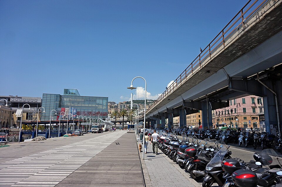 The waterfront walkway under the elevated road, lined with scooters