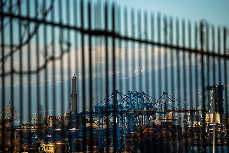 The container terminal seen through a railing on the walk to the Lanterna