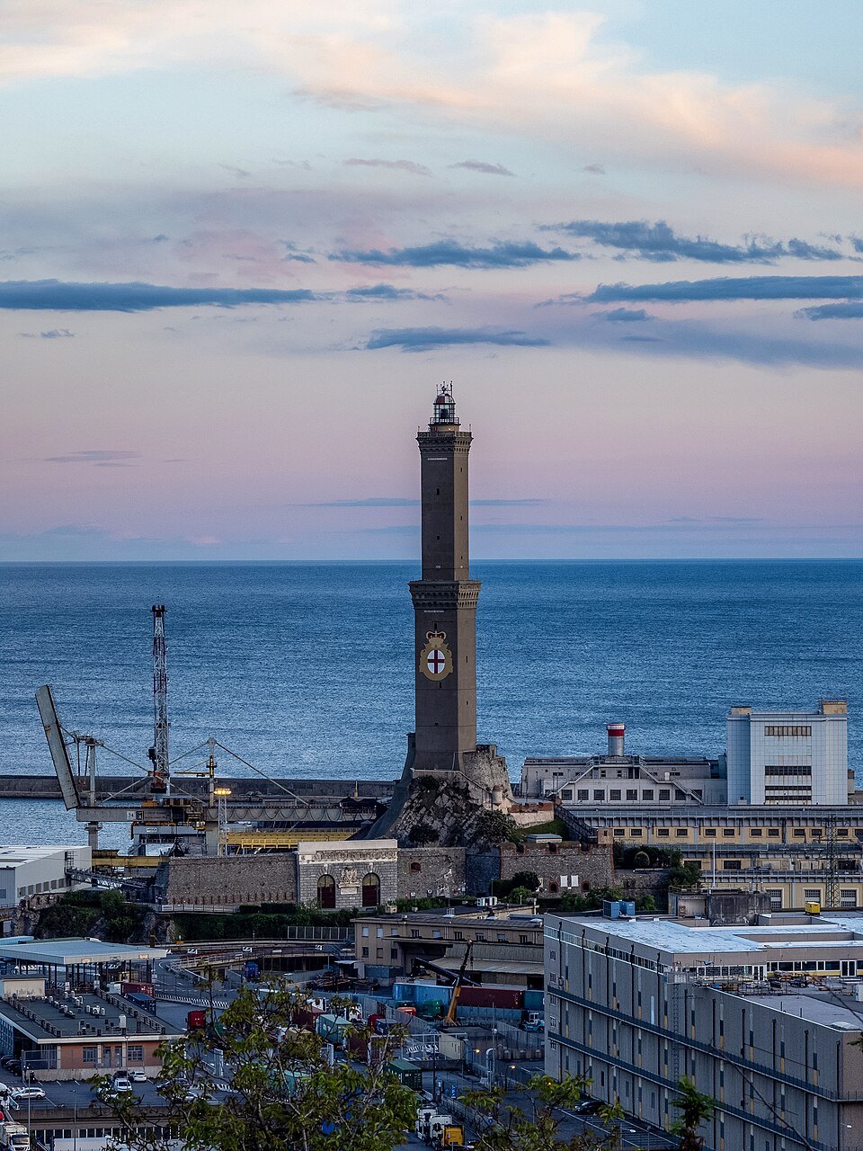 The Lanterna at dusk, the cross on its shaft above the port sheds and cranes