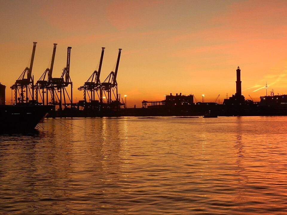 Sunset behind the container cranes, with the Lanterna in silhouette