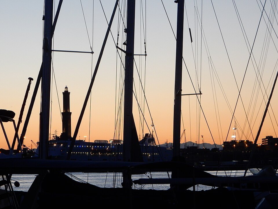 Yachts in the old port at dusk, the Lanterna lit behind the masts