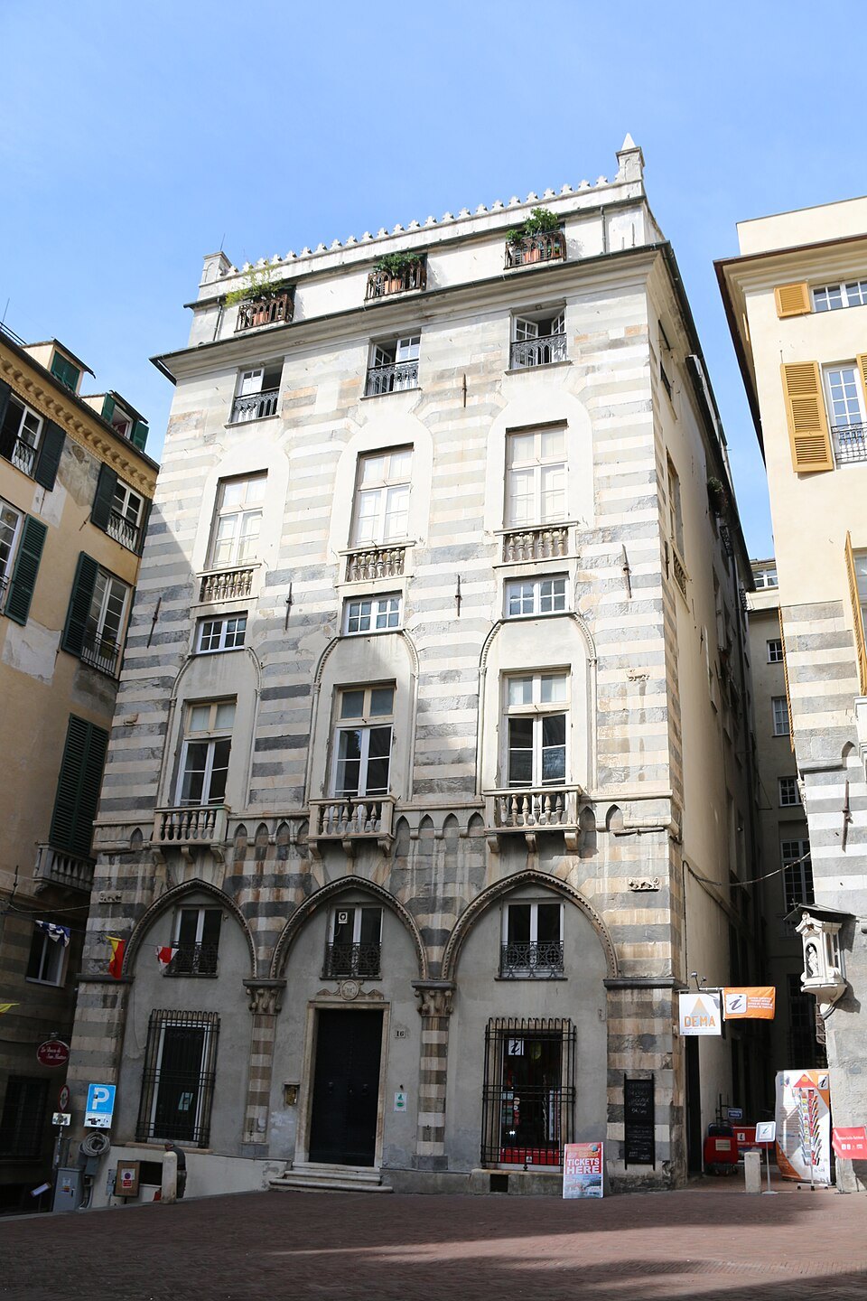 A corner palace with arcades along its ground floor, a lane opening beside it