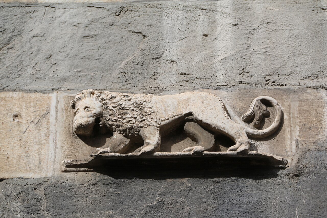 A carved lion in relief on a wall of the old town, the Doria badge at San Matteo