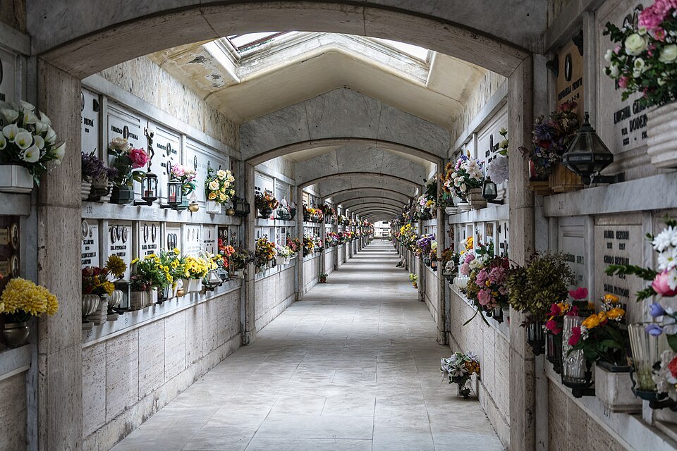 A gallery at Staglieno lined with tomb niches and flowers